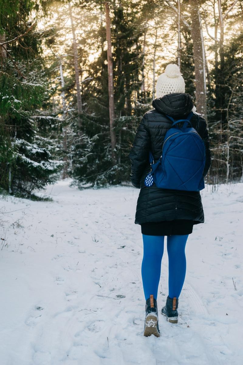 En dame går inn i en skog mens det er vinterl